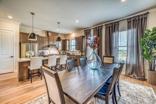 dining area featuring crown molding, recessed lighting, and light wood-style flooring
