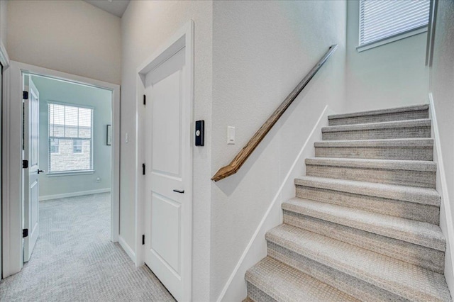 stairway featuring baseboards and carpet