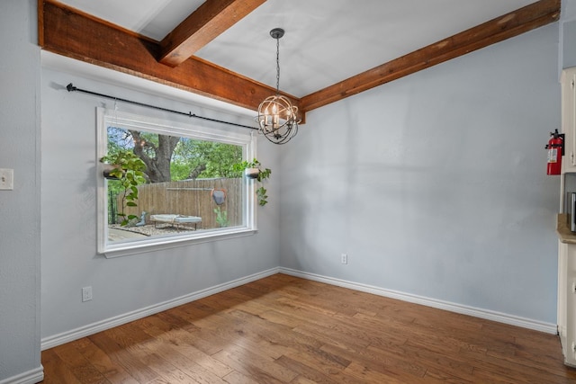 unfurnished dining area with baseboards, a chandelier, beam ceiling, and wood finished floors