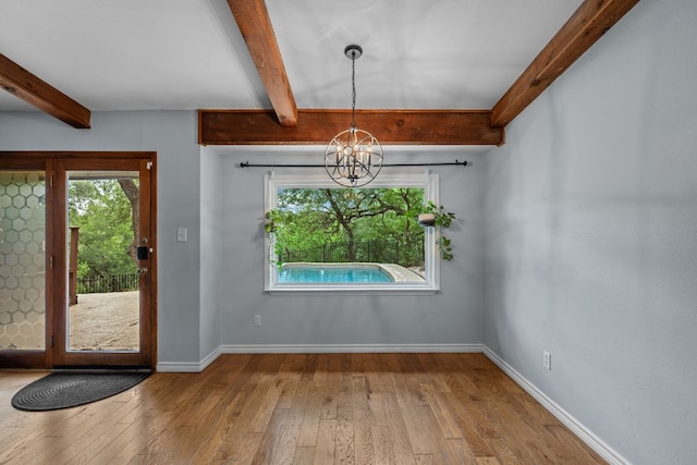 unfurnished dining area featuring a healthy amount of sunlight, beam ceiling, and a notable chandelier