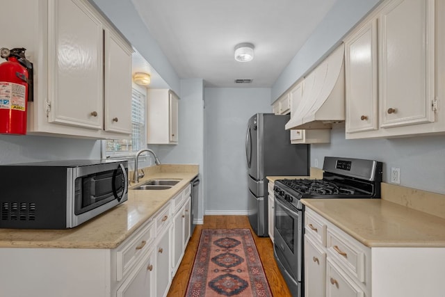kitchen with visible vents, wood finished floors, a sink, stainless steel appliances, and white cabinetry
