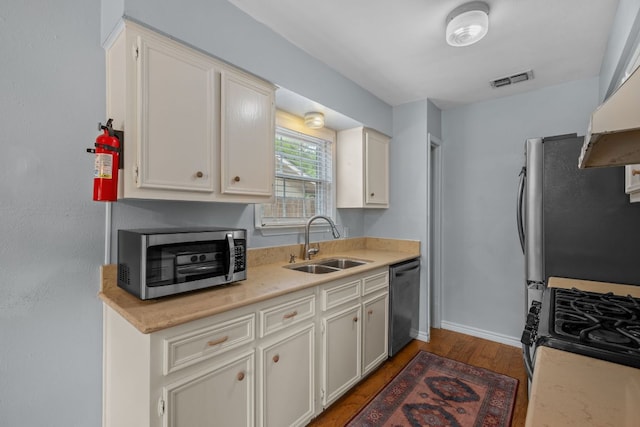 kitchen with appliances with stainless steel finishes, a sink, light countertops, wood finished floors, and visible vents