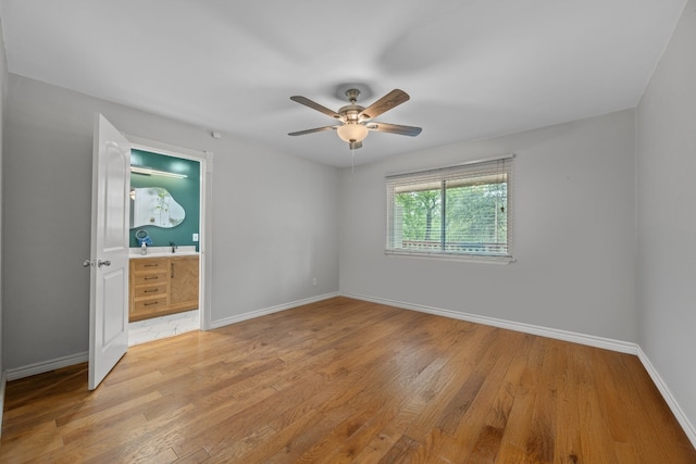 unfurnished bedroom with light wood-style floors, connected bathroom, baseboards, and a ceiling fan