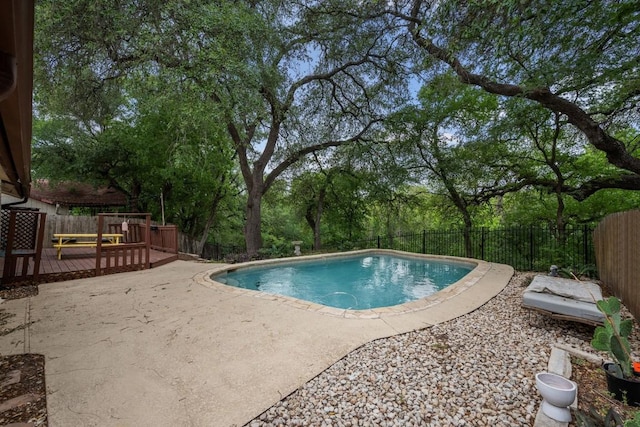 view of swimming pool with a fenced in pool, a wooden deck, a fenced backyard, and a patio
