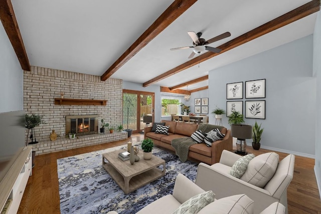 living room with a ceiling fan, a fireplace, wood finished floors, baseboards, and lofted ceiling with beams