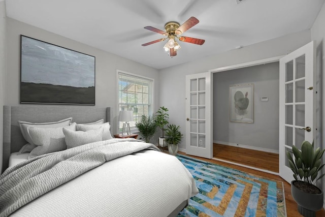 bedroom featuring baseboards, ceiling fan, french doors, and wood finished floors
