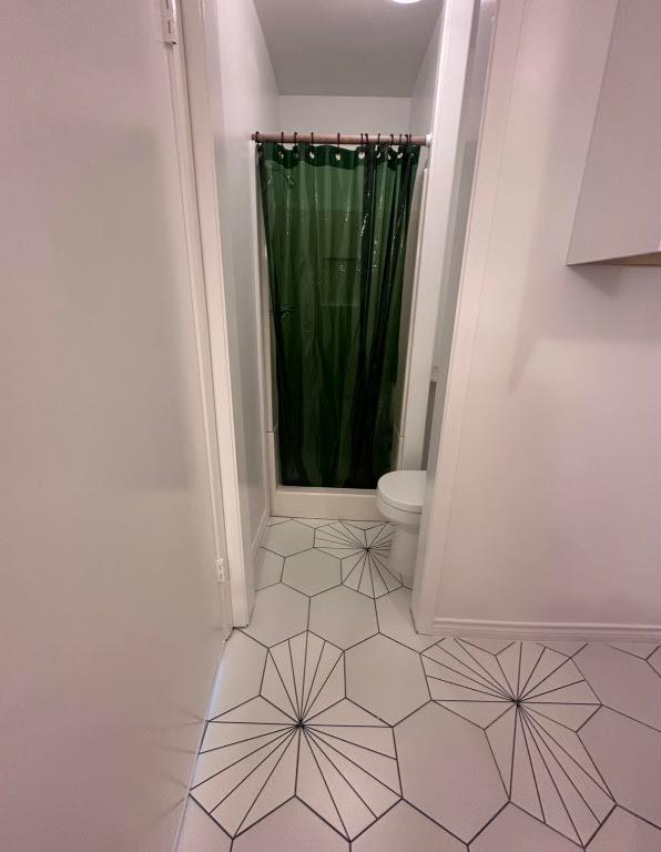 bathroom with baseboards, toilet, tile patterned floors, and curtained shower