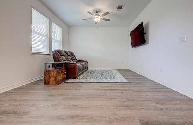 living area with visible vents, a ceiling fan, baseboards, and wood finished floors