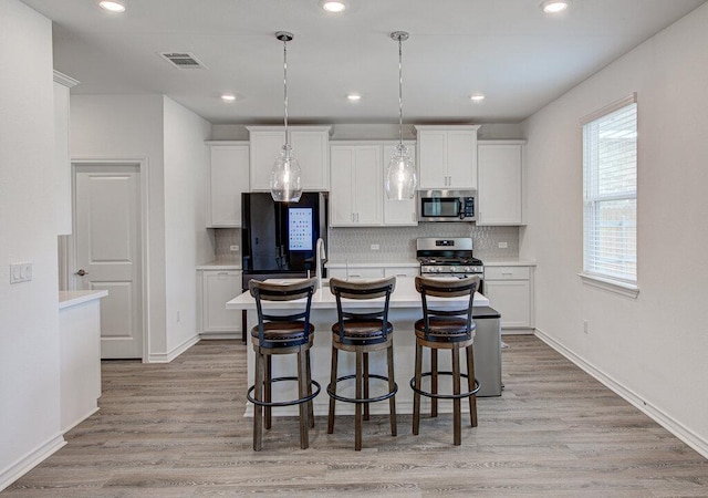 kitchen featuring white cabinetry, appliances with stainless steel finishes, decorative backsplash, and visible vents