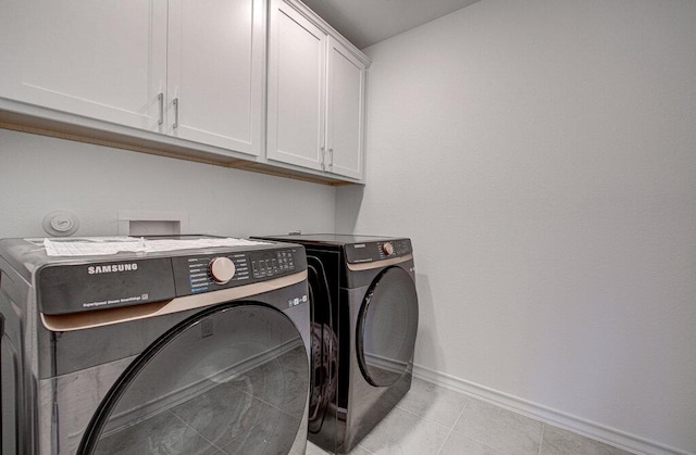 laundry room with light tile patterned floors, baseboards, cabinet space, and washing machine and clothes dryer
