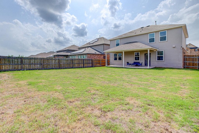 rear view of house featuring a lawn, a patio, and a fenced backyard