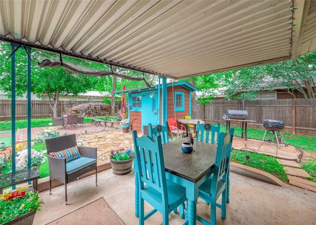1207 Flag St, Llano, TX 78643 - view of patio with a storage unit, a fenced backyard, an outbuilding, and outdoor dining space