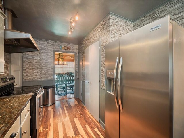 1207 Flag St, Llano, TX 78643 - kitchen featuring appliances with stainless steel finishes, under cabinet range hood, and wood finished floors