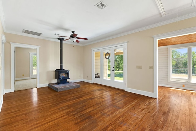 unfurnished living room with a wood stove, wood finished floors, and visible vents