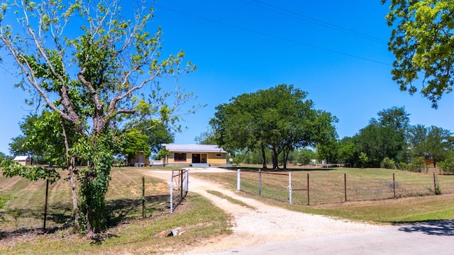 view of front of home featuring dirt driveway, a rural view, fence private yard, and a front yard