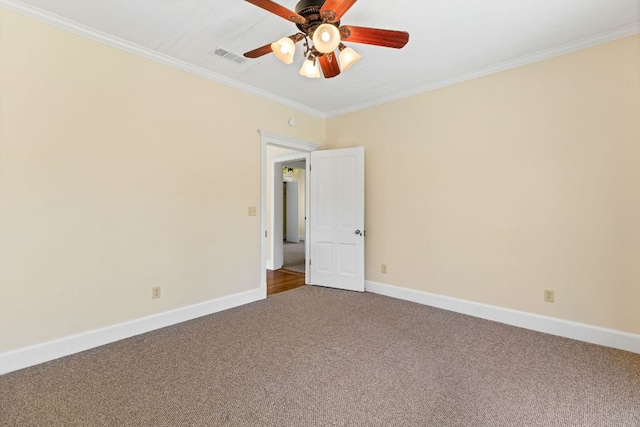 carpeted spare room with crown molding, ceiling fan, visible vents, and baseboards