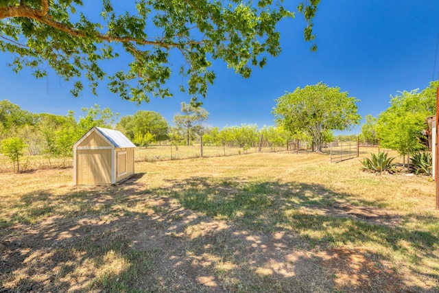 view of yard featuring fence, an outbuilding, a rural view, and a shed