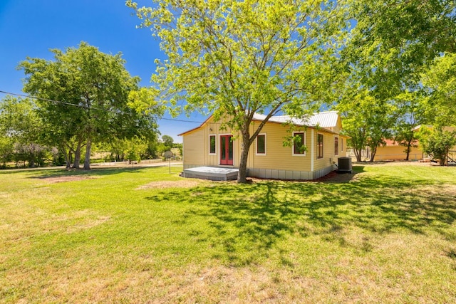 rear view of house with a lawn, metal roof, and cooling unit