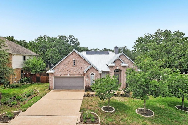 traditional-style house featuring driveway, a chimney, solar panels, brick siding, and a front lawn