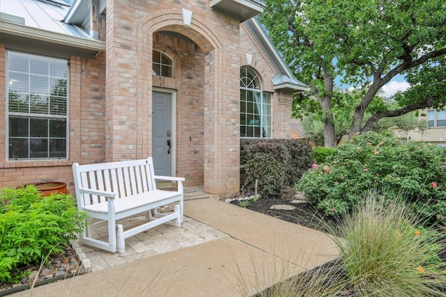 doorway to property with brick siding, metal roof, and a standing seam roof