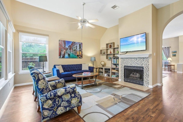 living area featuring ceiling fan, visible vents, arched walkways, wood finished floors, and baseboards