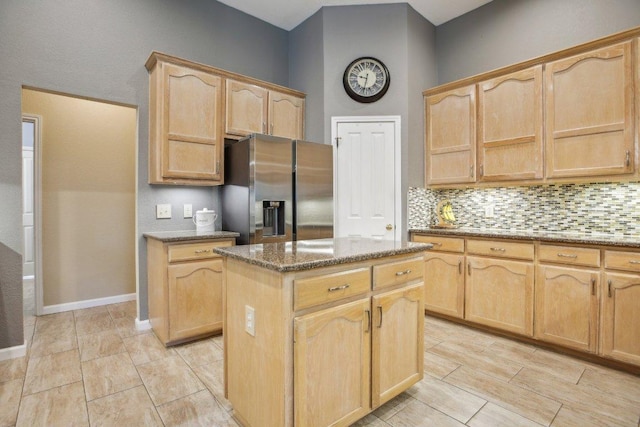 kitchen with stainless steel fridge with ice dispenser, light brown cabinets, a center island, stone counters, and tasteful backsplash