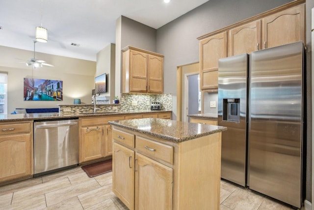 kitchen featuring a center island, stone countertops, appliances with stainless steel finishes, and light brown cabinets