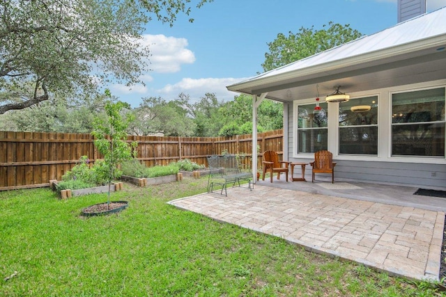view of yard with fence, a patio area, and a vegetable garden