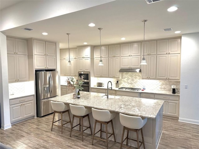 kitchen featuring visible vents, decorative backsplash, light wood-type flooring, a sink, and stainless steel appliances