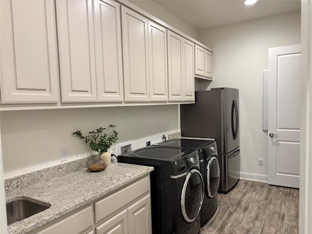 laundry area featuring washing machine and dryer, wood finished floors, a sink, baseboards, and recessed lighting