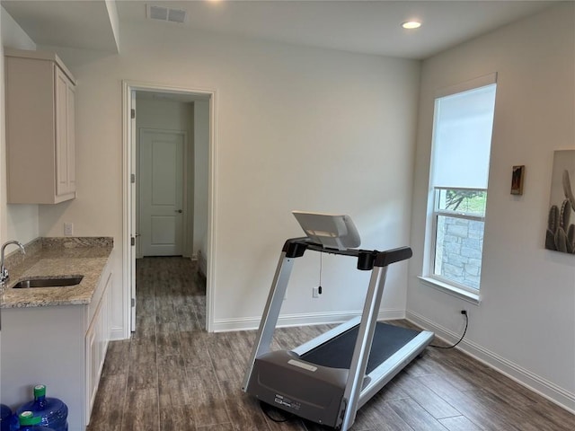 workout area with baseboards, visible vents, a sink, and dark wood-type flooring