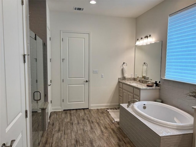 bathroom featuring a bath, visible vents, a shower stall, wood finished floors, and vanity