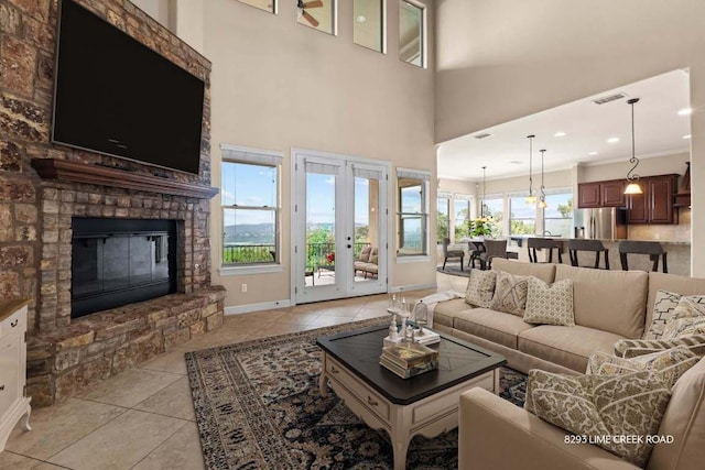 living room featuring light tile patterned floors, baseboards, a glass covered fireplace, and visible vents