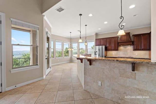kitchen with stainless steel fridge with ice dispenser, baseboards, a kitchen bar, visible vents, and custom exhaust hood