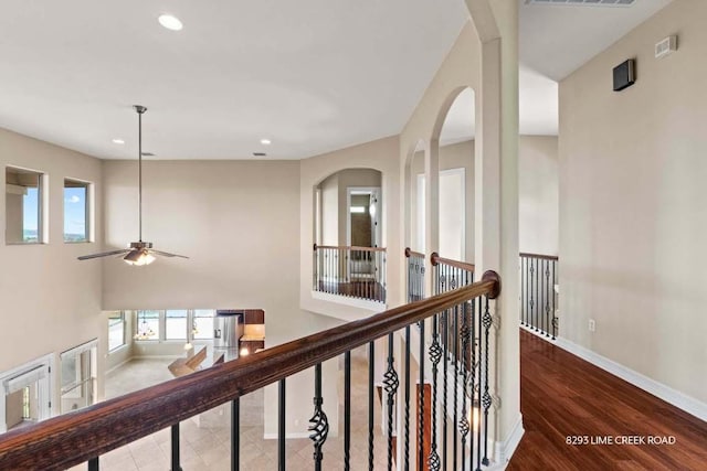 hallway with visible vents, arched walkways, wood finished floors, baseboards, and recessed lighting