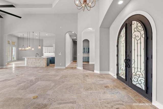 entrance foyer with an inviting chandelier, stone finish flooring, baseboards, and high vaulted ceiling