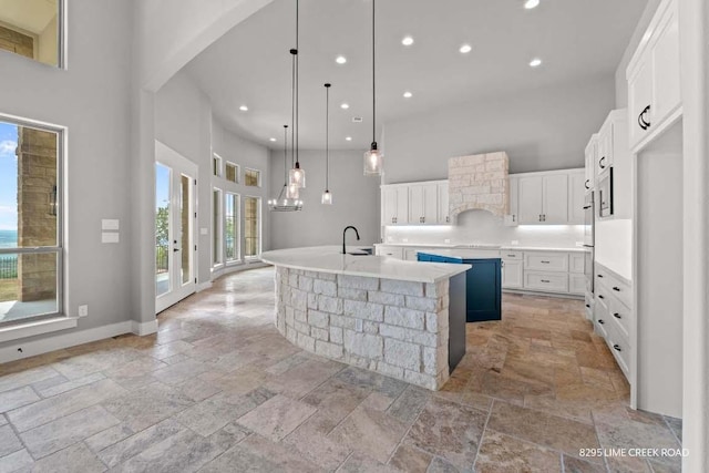 kitchen featuring stone tile floors, recessed lighting, a high ceiling, and a large island with sink