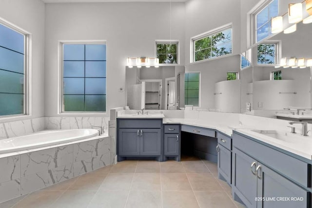 full bathroom featuring vanity, a high ceiling, tile patterned flooring, and a garden tub