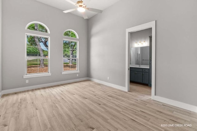 spare room featuring light wood-type flooring, a ceiling fan, and baseboards