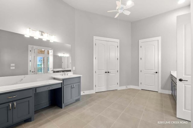 bathroom with vanity, a towering ceiling, baseboards, tile patterned floors, and a ceiling fan