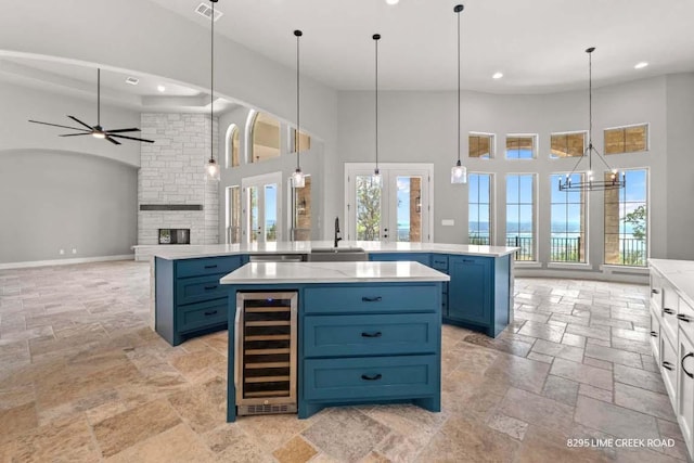 kitchen with stone tile flooring, a sink, wine cooler, and a high ceiling