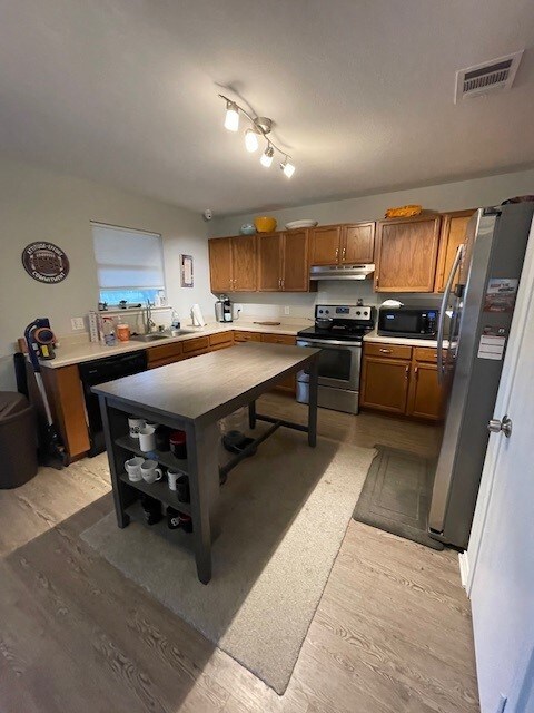3508 Sandy Brook Dr, Round Rock, TX 78665 - kitchen featuring visible vents, light wood-type flooring, under cabinet range hood, brown cabinets, and black appliances