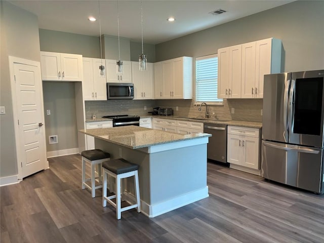 170 Nuuanu Rd, Bastrop, TX 78602 - kitchen with stainless steel appliances, a sink, a center island, white cabinets, and dark wood-style flooring