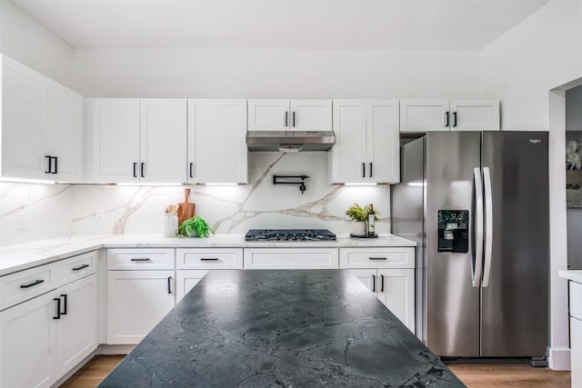 3838 Laurel Ridge Dr, Round Rock, TX 78665 - kitchen featuring appliances with stainless steel finishes, under cabinet range hood, white cabinetry, tasteful backsplash, and dark stone countertops