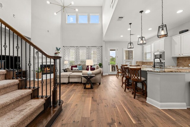 living area with visible vents, a towering ceiling, dark wood-style floors, stairway, and plenty of natural light