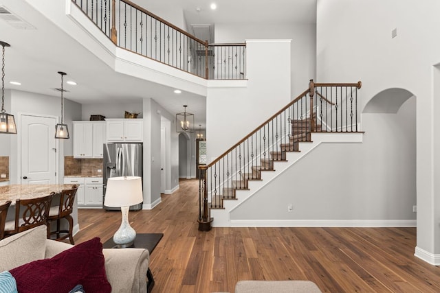 living area featuring arched walkways, baseboards, visible vents, and stairway