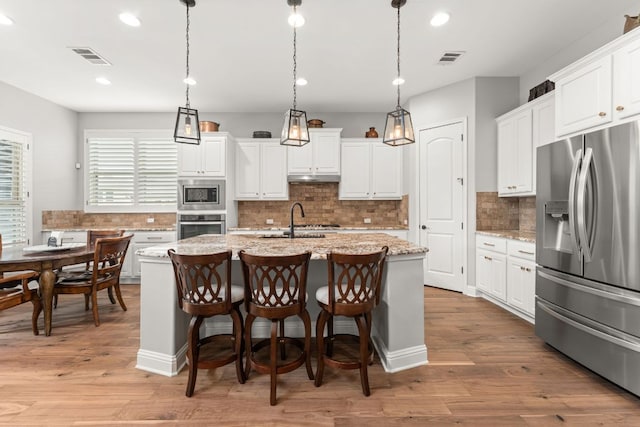 kitchen with a sink, backsplash, stainless steel appliances, and visible vents