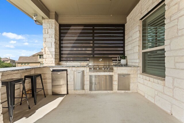 view of patio / terrace featuring an outdoor kitchen, exterior bar, and a grill