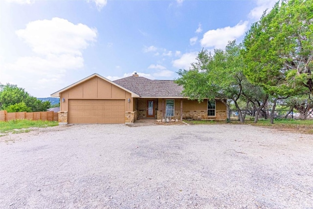 ranch-style house with board and batten siding, fence, stone siding, and a garage