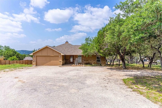 ranch-style house with an attached garage, fence, a chimney, and driveway